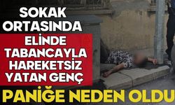 Sokak ortasında elinde tabancayla hareketsiz yatan genç paniğe neden oldu